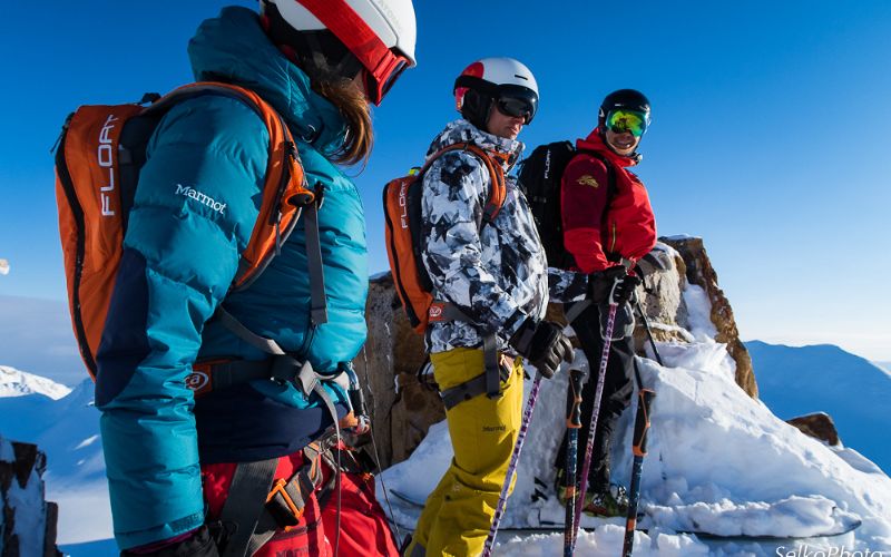 helicopter-skiing-three-skiers-standing-on-peak-min