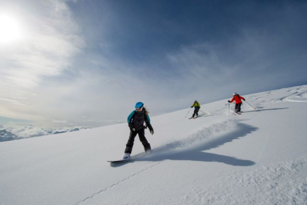 helicopter-skiing-three- skiers-heading-down-slopes-min