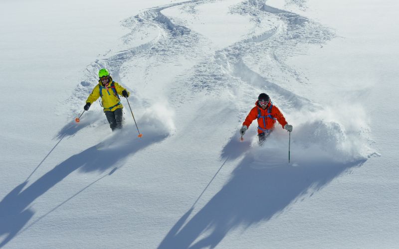 helicopter-skiing-two-skiers-side-by-side-min