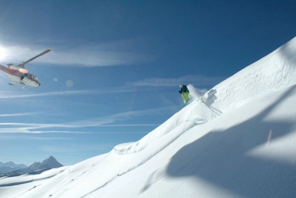 helicopter-skiing-skier-with-chopper-in-background-min